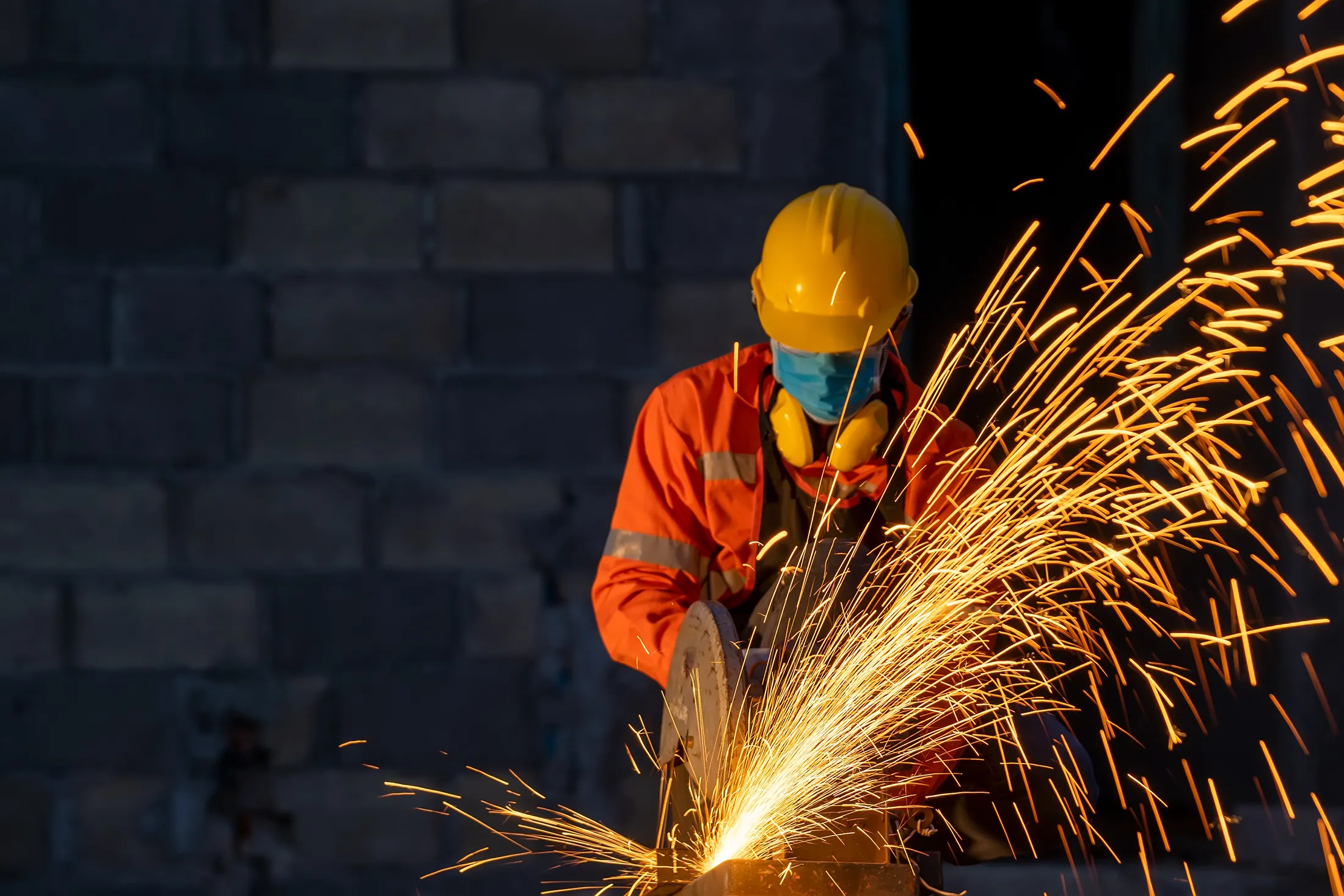 Industrial Steel Industrial photo of man in orange coveralls grinding steel and sparks flying